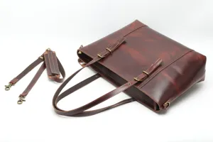 Close-up detail of dark brown leather tote bag showing fine stitching and robust metal hardware.