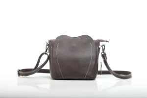 Detailed view of brown leather crossbody bag with curved top design and clean white stitching.