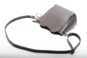 Brown leather shoulder bag detail showing texture, strap, and metal zipper hardware.