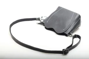 Detailed view of genuine leather black crossbody bag, showing fine texture and stitching.