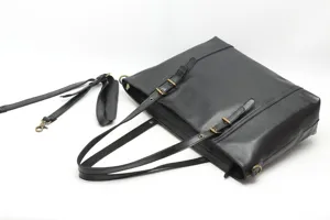 Detailed view of black genuine leather tote bag with metal buckles and shoulder strap.