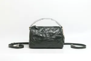 Detail shot of dark green genuine leather Boston handbag, vintage style shoulder bag.