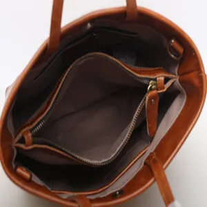 Brown genuine leather tote bag top view showing spacious interior compartments and lining.