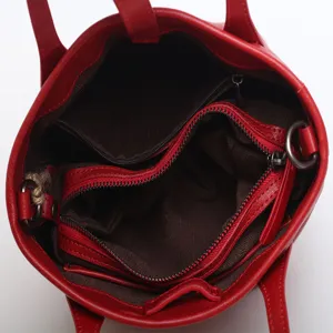 Red leather bucket bag interior view, premium cowhide tote with zipper compartments.
