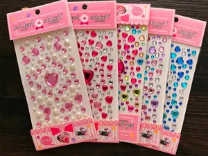 Close-up detail of colorful 3D heart and round gemstone stickers on pink retail cards