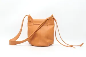 Detail shot of caramel brown leather bucket bag, showing fine texture, stitching and strap.
