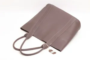 Taupe genuine leather tote bag detail showing fine cowhide texture, minimalist handbag.