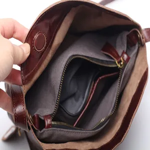 Brown genuine leather saddle bag interior view with secure zipper compartments and fabric lining.