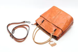Detail view of genuine leather bucket bag with hanging tag and adjustable strap, fine texture.