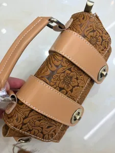 Close-up detail of vintage genuine leather embossed cylindrical handbag with metallic turn-lock.