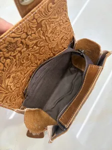 Close-up detail view of vintage floral embossed leather bag interior and zipper pocket.