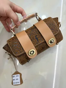 Detailed view of retro embossed genuine leather barrel handbag with metal turn-lock closure.