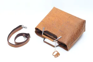 Detailed view of the vintage embossed leather handbag featuring metal handles and strap.