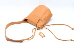 Detailed view of genuine leather bucket shoulder bag in caramel brown with drawstring.