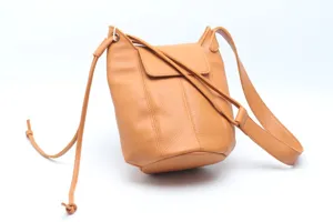Detail view of a camel leather bucket bag featuring a secure flap closure and shoulder strap.