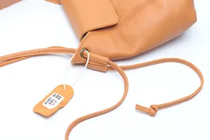 Detail view of the stylish cowhide leather shoulder bag with drawstring closure and tag.