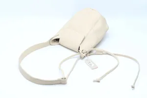 Close up detail view of beige leather shoulder bag strap and tag, minimalist chic quality.
