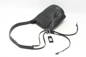 Black genuine leather bucket bag detail view displaying texture, strap and tags.