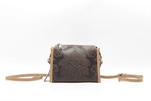 Detailed view of a retro brown leather embossed crossbody bag with fine floral pattern and strap.