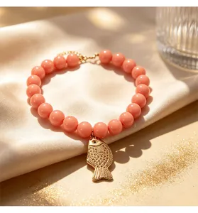 Gros plan détaillé du bracelet de perles roses avec un charmant pendentif poisson or.