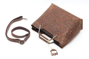 Detailed view of vintage embossed genuine cowhide leather handbag with metal handle and strap.