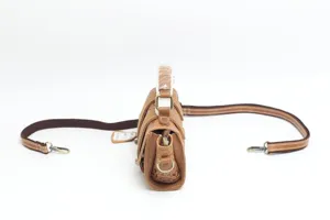 Side detail view of vintage embossed leather handbag with metal hardware and strap.