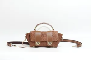 Detailed view of the brown embossed leather handbag, featuring floral tooling and metal locks.