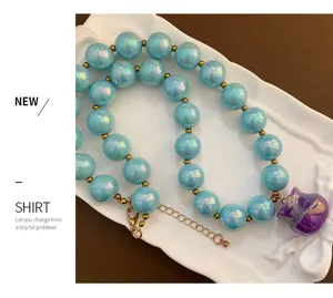 Collana di perle rotonde in acrilico colorato boho con distanziatori dorati e ciondolo.