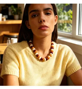 Detail shot of a bohemian chunky resin bead necklace worn by a model in a cafe setting.