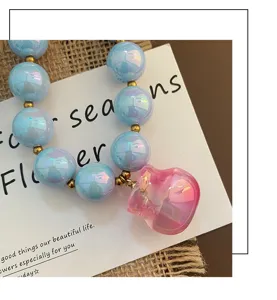Collana chic di perline acriliche colorate con distanziatori dorati e ciondolo rosa.
