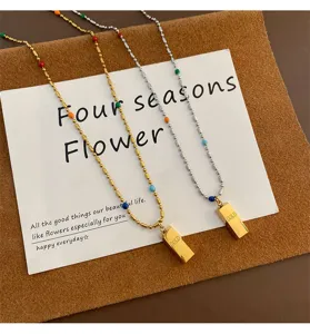 Detailed shot of titanium steel colorful bead necklaces with small gold brick pendants.