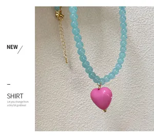 Vue détaillée d'un collier de perles bleues tendance avec pendentif cœur rose vif.
