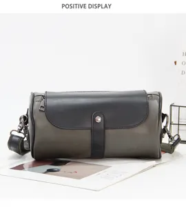 Detail view of men's dark grey cylinder shoulder bag with black flap and metal snap.