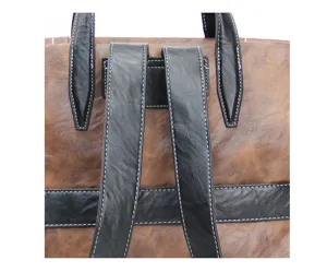 Gros plan des détails des bretelles de sac à dos en cuir marron et noir avec coutures.