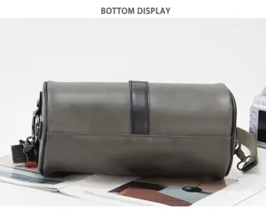 Detail view of men's gray cylindrical shoulder bag bottom design and hardware.