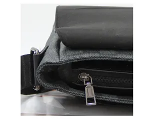 Detailopname van heren leren schoudertas met klassiek ruitpatroon en handige ritssluiting.