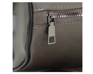 Detailed view of men's cylindrical bag zipper, premium hardware, neat stitching texture.
