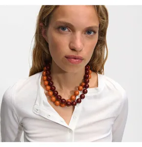 Detailed view of the layered beaded necklace with red and orange round acrylic beads.
