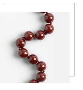 Close-up detail shot of a stylish dark red acrylic beaded necklace with smooth round beads.