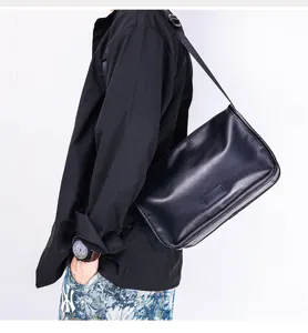 Detail shot of the black leather messenger bag worn by a model, showing strap and texture.