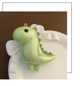 Gros plan d'un charmant pendentif de dinosaure vert clair brillant pour accessoires de clés.