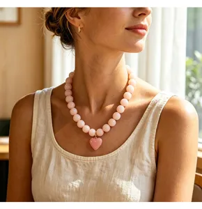 Gros plan détaillé d'un collier de perles en acrylique rose avec pendentif cœur sur modèle.