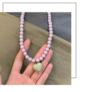 Gros plan sur le collier de perles minimaliste avec un joli pendentif cœur aux tons pastel.