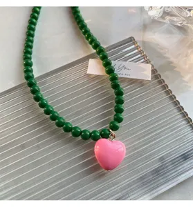 Gros plan d'un collier de perles vertes élégant avec un pendentif cœur rose brillant au quotidien.