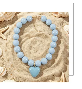 Vue détaillée du collier de perles en acrylique bleu clair avec pendentif cœur de plage.
