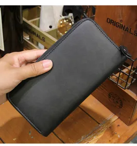 Detail view of black long zipper wallet, PU leather texture, card slots and cash pocket.