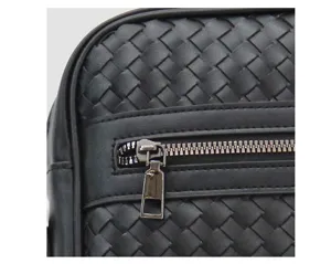 Close-up detail of black leather woven men bag featuring smooth zipper pocket craftsmanship.