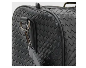 Black woven leather travel bag detail shot showing premium craftsmanship and hardware.