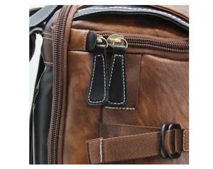 Close-up detail of vintage brown leather backpack zipper, durable pull tab and strap buckle.
