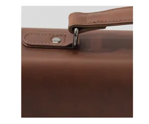 Close-up detail of vintage brown leather briefcase handle and metal hardware elements.